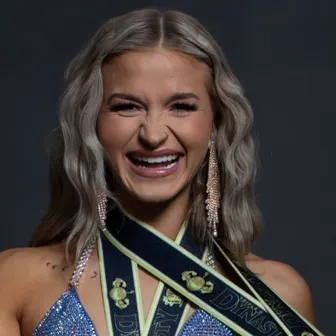 AK Vallejos laughing, with competition medal ribbons around her neck.