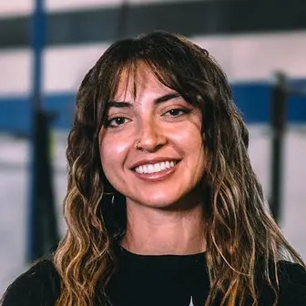 Denae Preuhs smiling, in a black T-shirt, in a gym.